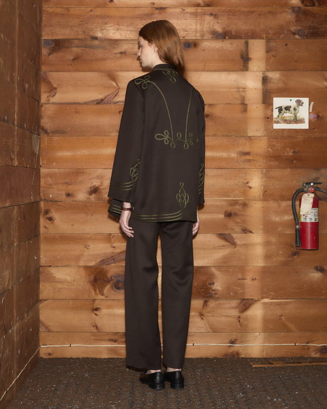 Back view of a person wearing a Cavalry Coat in wool with gold soutache trim and matching trousers.
