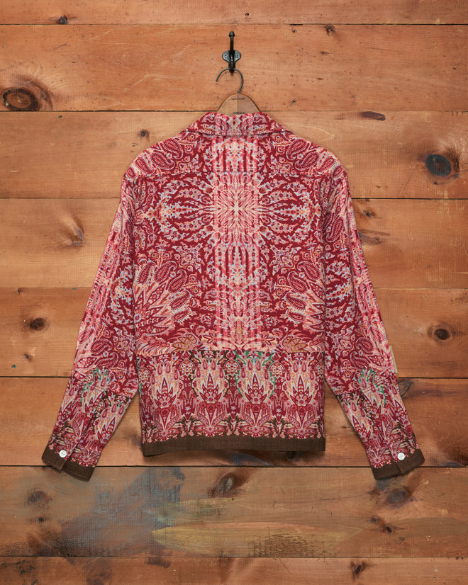 Arrowleaf Long Sleeve Shirt featuring intricate designs and a subtle paisley print hangs on a wooden wall, viewed from the back.