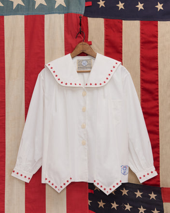The Red Star Blouse features red star trim on the collar and cuffs, displayed against an American flag—perfect for Liberty costumes or Fourth of July celebrations.