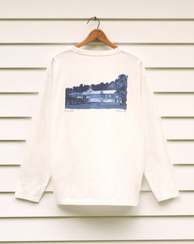 School of Music Tee in white with long sleeves, featuring a house illustration on the back, displayed on a hanger against white siding—ideal for fans of the Norfolk Chamber Music Festival or anyone who treasures summer memories at the Yale School of Music.