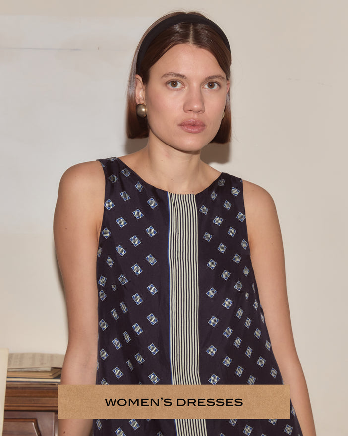 A woman wearing a dark blue dress that has stripes down the front placket and a diamond motif pattern.