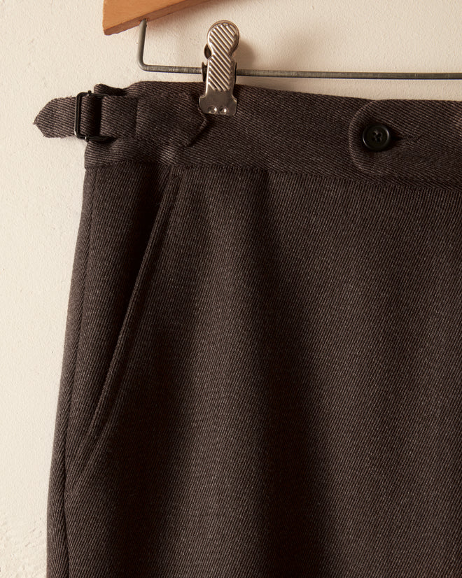 Close-up of Twill Side Buckle Trousers - Black, made from 100% wool, featuring a button, clip, and side pocket. These trousers combine classic style and functionality for the modern wardrobe.